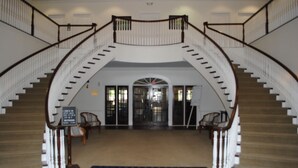 A grand staircase with a curved design, leading to an arched doorway. - Beautiful Second Floor 2-Bedroom Two-Bath Condo With Water and Golf Views (Calabash)