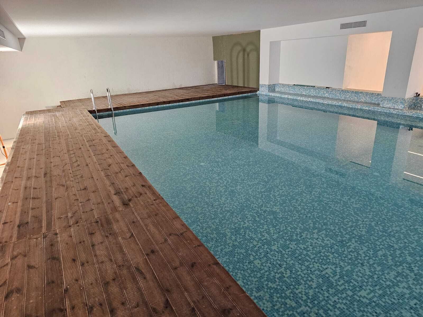 Una piscina interior con cubierta de madera y paredes de azulejos.