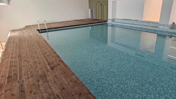 Una piscina interior con cubierta de madera y paredes de azulejos.
