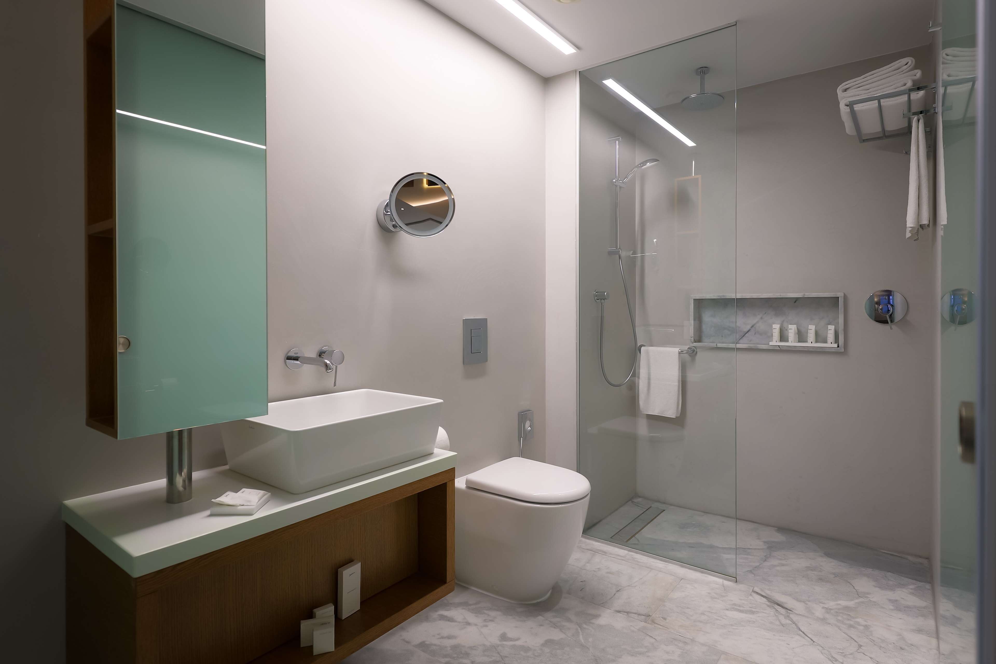 Un baño moderno con un lavamanos grande, inodoro y ducha con mampara de vidrio.