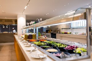 A buffet with various food options, including salads, fruits, and vegetables.