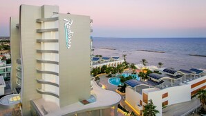 A Radisson hotel with a pool, solar panels, and a view of the sea. - Radisson Beach Resort Larnaca (Oroklini)