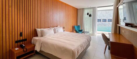 A hotel room with a bed, a desk, a chair, a telephone, and a window with a view of a building and a pool.