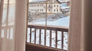 Blick aus dem Fenster auf ein Gebirge mit einem Gebäude im Vordergrund.