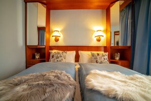 Habitación de hotel con dos camas, cabecero de madera, lámparas fijadas a la pared y un espejo.