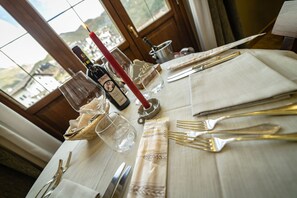 Una mesa dispuesta para comer, con una botella de vino, copas, cubiertos y una vela.