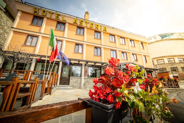 Un hotel con fachada amarilla, múltiples ventanas y una bandera.
