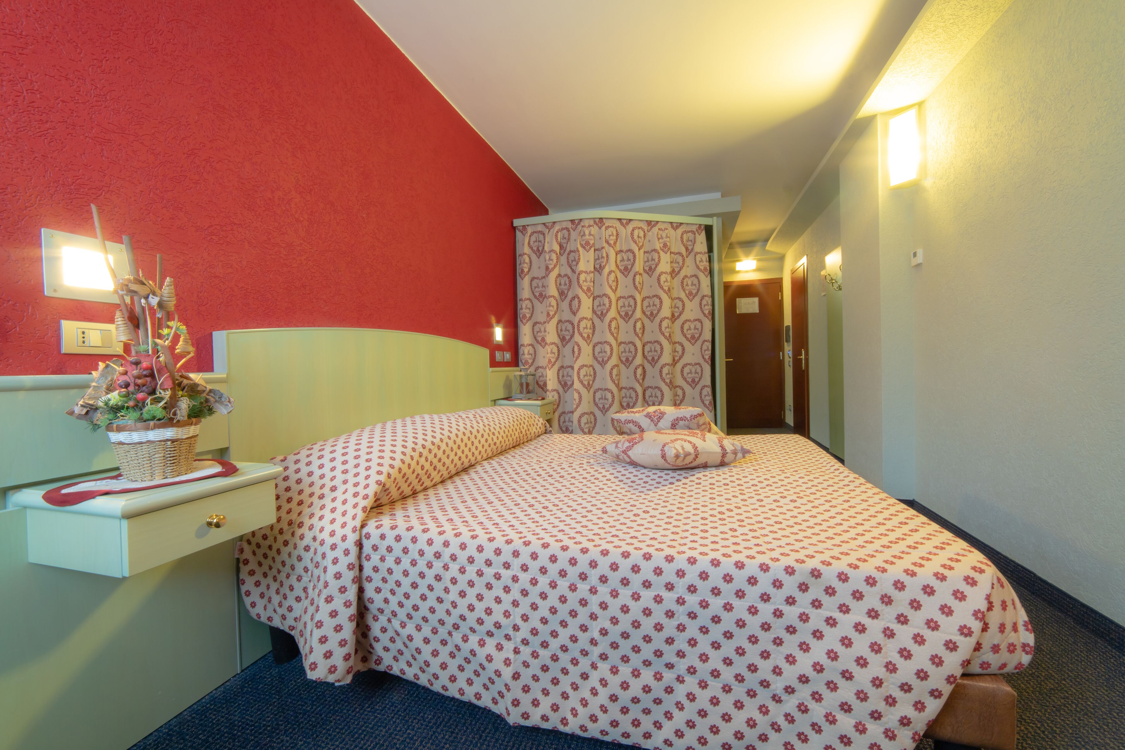 A hotel room with a bed, a nightstand, a lamp, and a wall-mounted light.