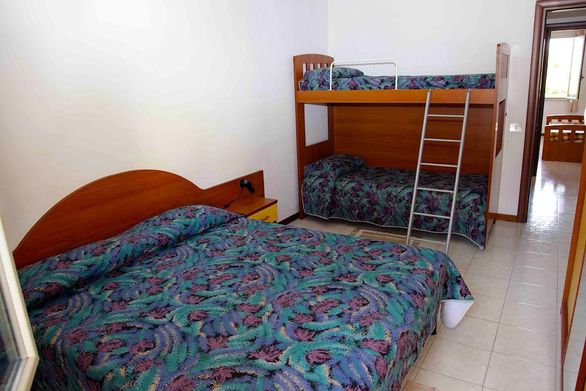 Un dormitorio con dos literas, un cabecero de madera y una colcha estampada.