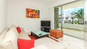 Un salon moderne avec un canapé, une table basse, un téléviseur et un tableau abstrait aux couleurs vives.