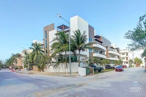 A modern hotel with multiple floors, balconies, and palm trees.
