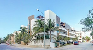 A modern hotel with multiple floors, balconies, and palm trees.