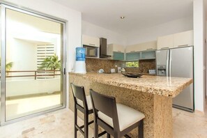 A kitchen with granite countertops, a water dispenser, a microwave, and a refrigerator.