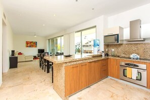A modern kitchen with granite countertops, wooden cabinets, a built-in oven, and a microwave.