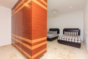 A bedroom with two beds, a wardrobe, and a ceiling fan.