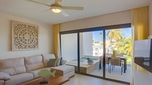 Un soggiorno moderno con divano, tavolino e opere d'arte. Si nota una ventola a soffitto e una porta scorrevole in vetro che dà su una zona esterna con tavolo e sedie.