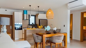 Una cucina moderna con zona pranzo, caratterizzata da un tavolo di legno, due sedie e una lampada a sospensione.