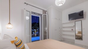 A bedroom with a bed, a TV, a wardrobe, and a sliding door to an outdoor area. - Soso's Garden Villa with Private Pool (Zakynthos)