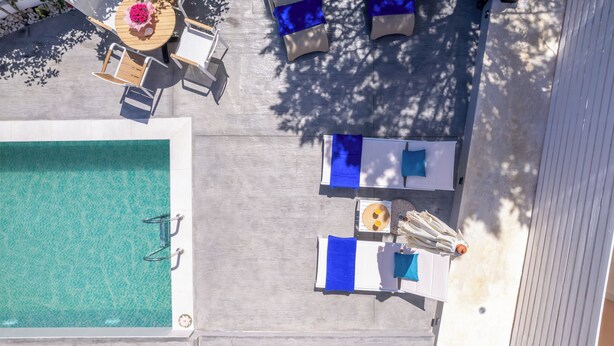 An aerial view of a pool area with a rectangular pool, lounge chairs, and umbrellas. - Soso's Garden Villa with Private Pool (Zakynthos)
