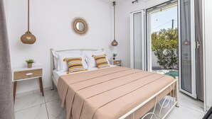 A bedroom with a bed, bedside tables, a mirror, and a view through a sliding glass door. - Soso's Garden Villa with Private Pool (Zakynthos)