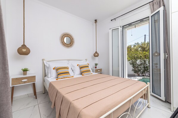 Een slaapkamer met een bed, nachtkastjes, een spiegel en uitzicht door een schuifdeur.