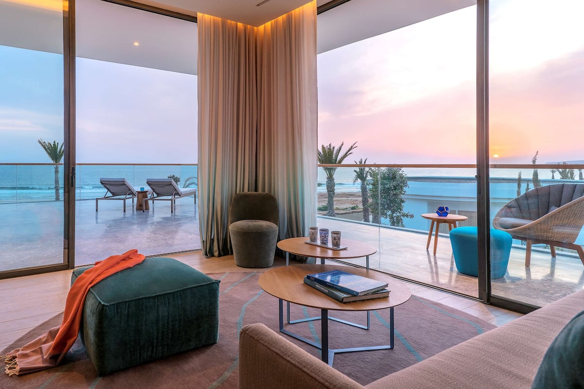 A modern room with a large glass door leading to a balcony overlooking the ocean.