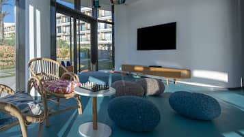 A modern lounge area with wicker chairs, a round table, and blue bean bags.