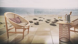 A beachside seating area with a wicker chair and a table, a bottle of champagne, and two glasses of wine. - Hyatt Regency Taghazout  (Taghazout)