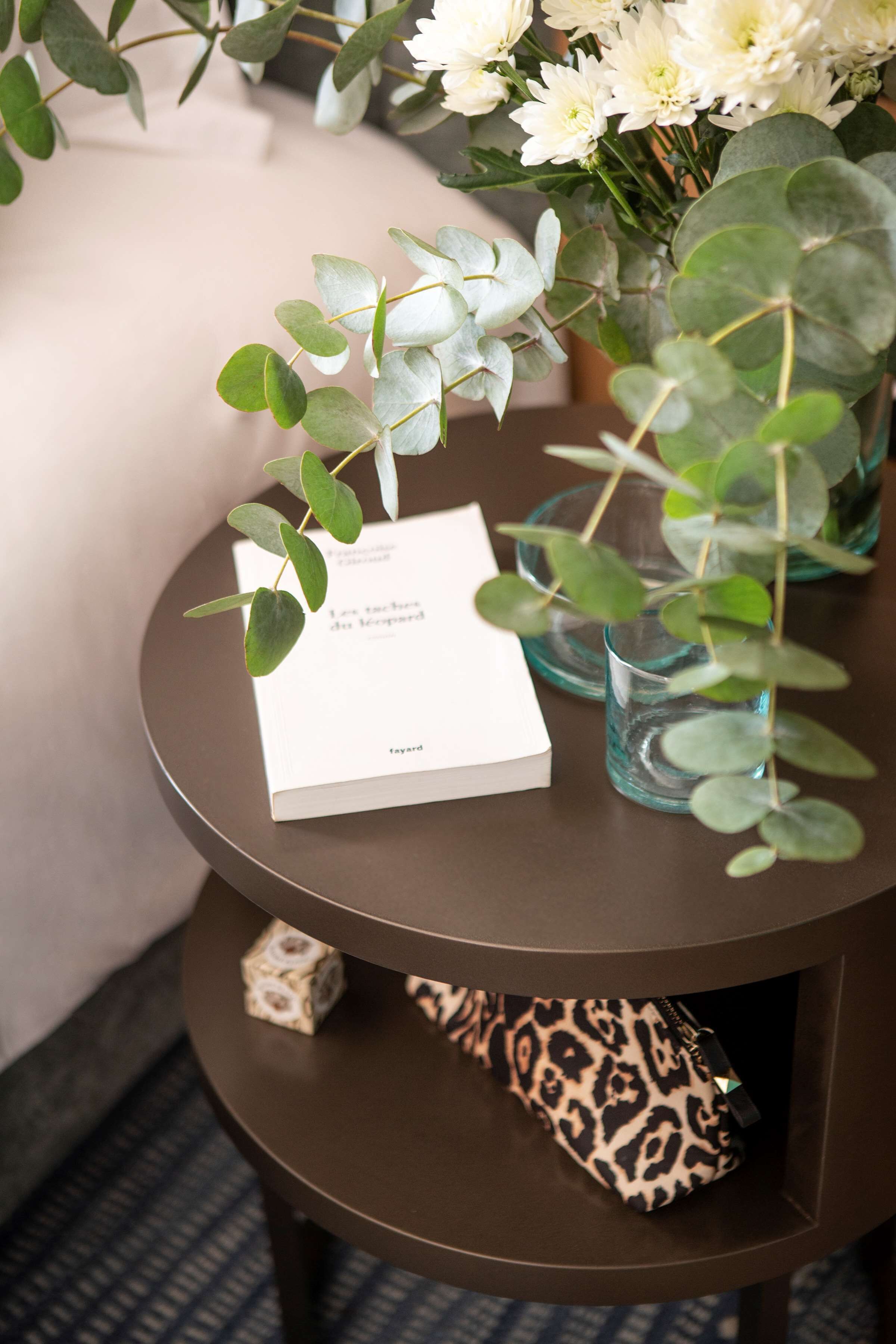 A round table with a book, a glass, and a leopard print bag.