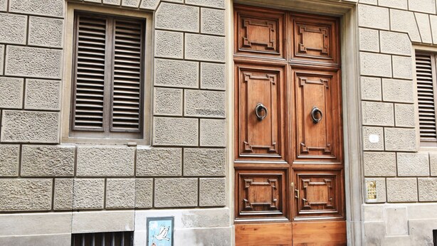 A wooden double door with a traditional design, set in a building with a stone facade.