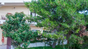 Un edificio residencial con balcón, rodeado de exuberante vegetación y árboles.