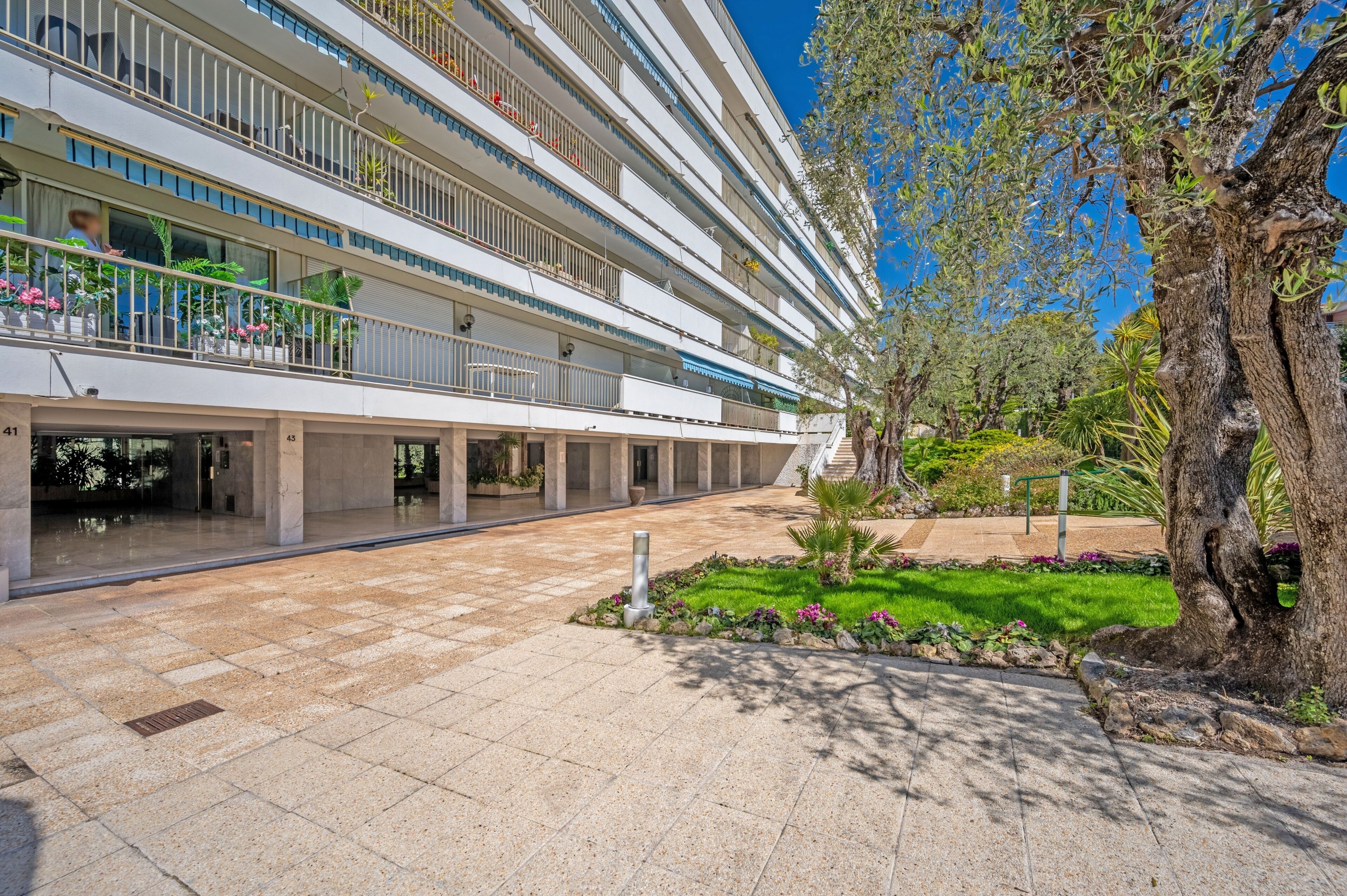 A multi-story hotel with balconies, a courtyard, and a large tree.