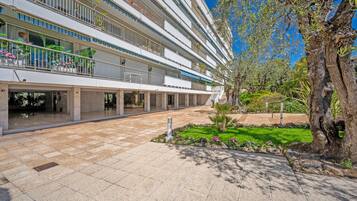 A multi-story hotel with balconies, a courtyard, and a large tree.