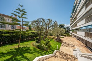 A hotel courtyard with a well-maintained lawn, a palm tree, and a staircase leading to the building.