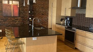 A modern kitchen with a central island, stainless steel appliances, and a brick wall. - Boston Harbor views. Modern north end condo.FREE PARKING! (Boston)