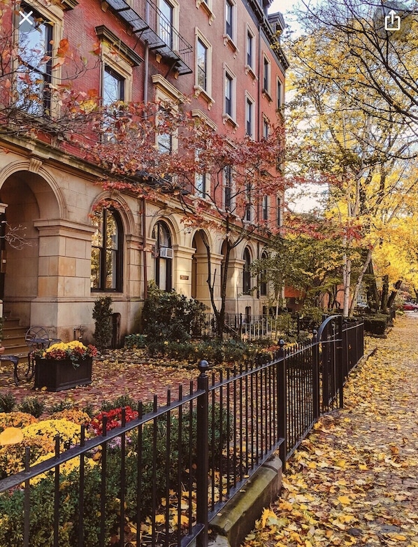 A row of red brick townhouses with arched windows and a black metal fence in front.