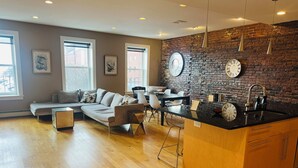 A modern living room with a sofa, dining table, and kitchen island. - Boston Harbor views. Modern north end condo.FREE PARKING! (Boston)