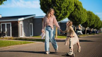 A woman holding a child's hand, both walking on a paved path.