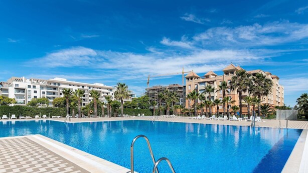 A swimming pool with a checkered border, surrounded by palm trees and lounge chairs. - LAS ARENAS 235 - Two Bedroom Apartment, Sleeps 5 (Punta del moral)