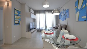A modern living room with a glass dining table, a sofa, and artwork on the walls. - LAS ARENAS 235 - Two Bedroom Apartment, Sleeps 5 (Punta del moral)