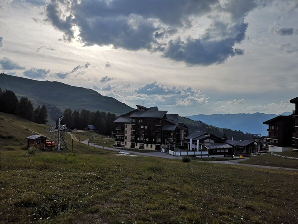 A mountain resort with multi-story buildings, a ski lift, and a clear view of the surrounding mountains.