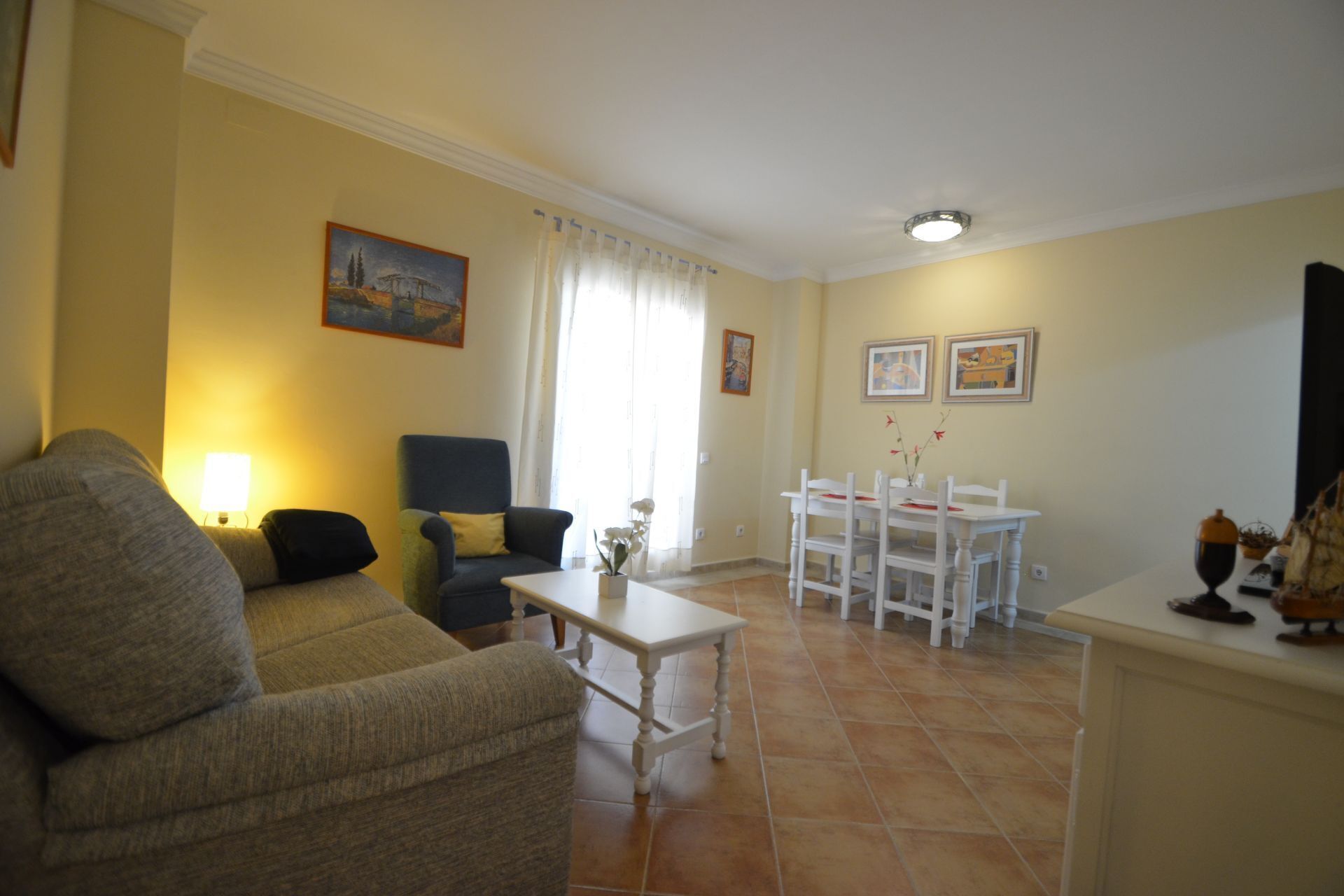 A living room with a sofa, armchair, table, and a dining area with chairs and a table.