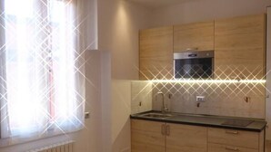 A modern kitchen with wooden cabinets, a stainless steel sink, and a built-in oven. - Giudei House Minisuite (Bologna)