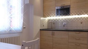 A kitchen with wooden cabinets, a black countertop, and a window with blinds. - Giudei House Minisuite (Bologna)