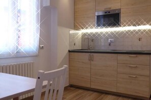 Compact kitchen with oven, microwave, and light-colored cabinets.