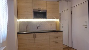 A modern kitchen with wooden cabinets, a microwave, and under-cabinet lighting. - Giudei House Minisuite (Bologna)