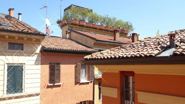 A row of terracotta-roofed buildings with shuttered windows and balconies. - Giudei House Minisuite (Bologna)