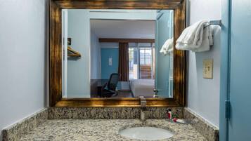 Un baño con encimera de granito, un lavabo, un espejo con marco de madera y un perchero.