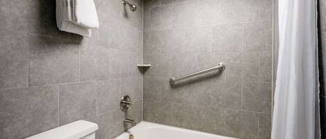 A modern bathroom with a bathtub, toilet, and shower area.