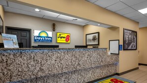 Een hotel receptie met een granieten balie, een 'Days Inn by Wyndham' bord, een 'Super 8' bord en een bord met informatie over toegankelijkheid voor rolstoelen.
